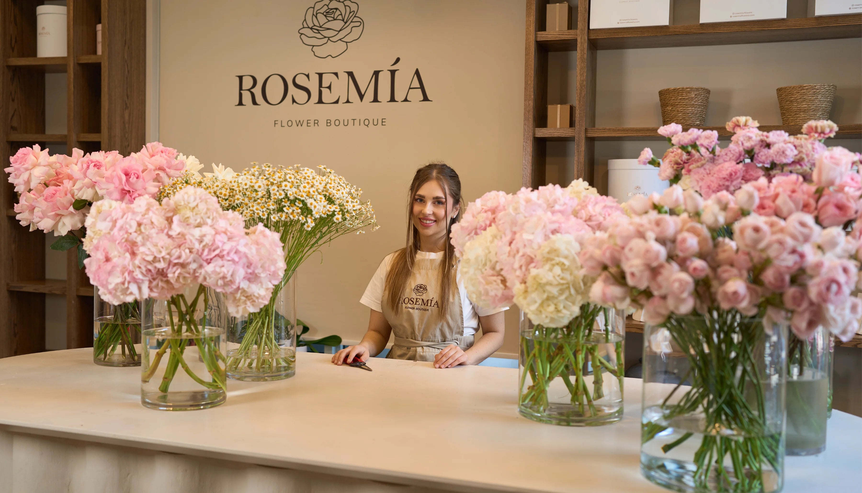 Woman behind a counter with flower bouquets at Rosemia Flower Boutique