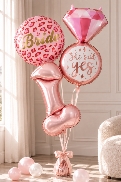 A bridal shower balloon bouquet set in a bright room, featuring a pink leopard print balloon with 'Bride' in gold foil, a pink diamond-shaped balloon, a round balloon reading 'She said yes' in rose gold foil, and metallic rose gold lip-shaped and heart-shaped balloons.